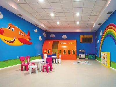 Colorful kids' play area with airplane and rainbow wall art, small chairs, and tables.