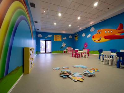 Colorful children's playroom with rainbow, clouds, and a red airplane on the wall.