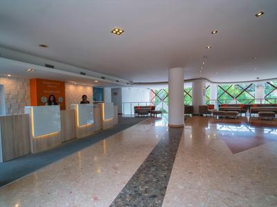 Bright hotel lobby with reception desks and seating area near large windows