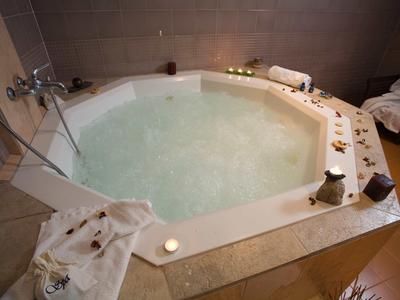 A water-filled hot tub in a bathroom, surrounded by candles and towels.
