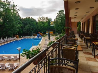 View from balcony overlooking hotel pool with lounge chairs and seating areas on a cloudy day.