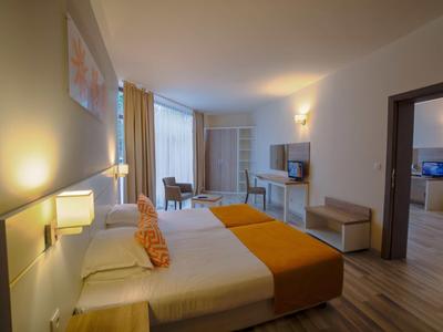 Modernly furnished hotel room with double bed, TV, and access to an adjoining room.