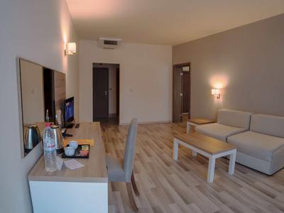 Modern hotel room with sofa, desk, and TV.