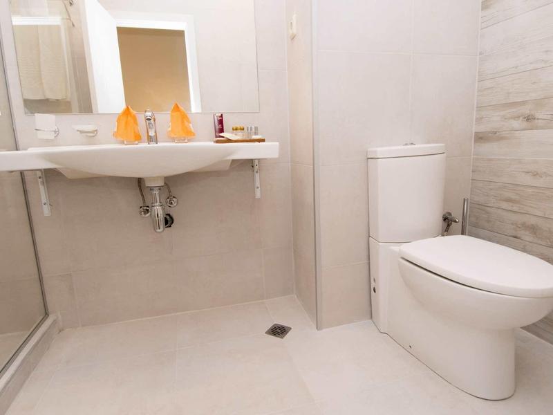 Clean, modern bathroom with white toilet, sink, and light tiled floor.
