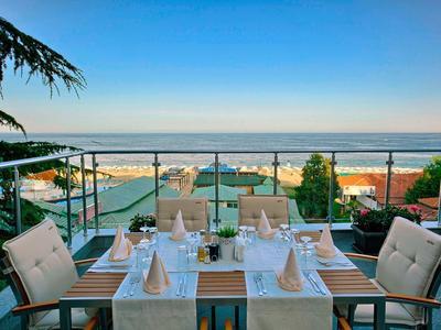 Restaurant en terrasse avec table dressée surplombant la mer sous un ciel dégagé