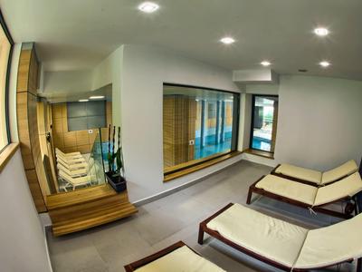 Salle de bien-être lumineuse avec transats, étagères en bois et grand miroir près de la fenêtre