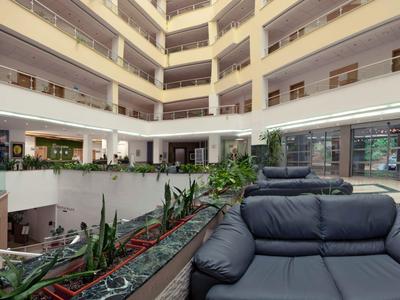 Nowoczesna lobby hotelowa z donicami na rośliny i wygodnymi skórzanymi fotelami w neutralnych kolorach.