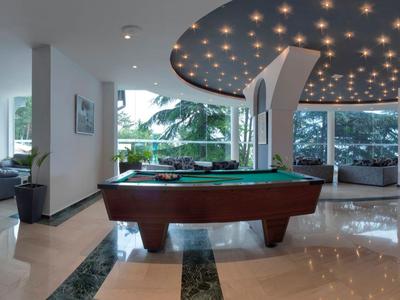 Nowoczesna strefa gier z bilardem, wygodnymi miejscami do siedzenia i dużym widokiem z okna.