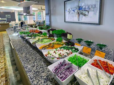 Buffet avec divers légumes frais dans des bols blancs sur un comptoir en marbre gris.