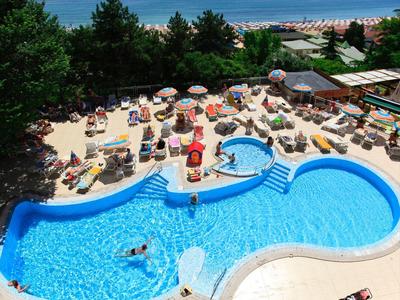 Piscine d'hôtel avec bar piscine, transats, entourée d'arbres et vue sur la mer.