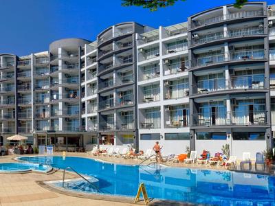 Nowoczesny kompleks hotelowy z basenem i leżakami pod jasnym, niebieskim niebem