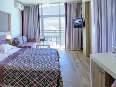 Chambre d'hôtel moderne avec lit double, balcon et vue sur la mer.