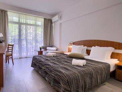 Chambre d'hôtel moderne avec lit double, bureau, balcon et lumière naturelle.