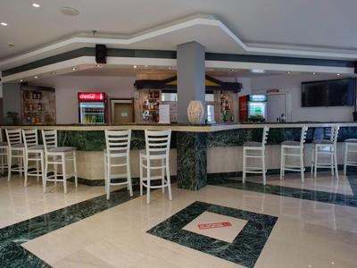 Nowoczesny bar hotelowy z białymi krzesłami i zielonym marmurowym blatem