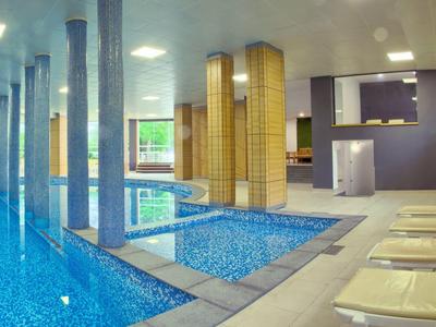 Piscine intérieure moderne avec chaises longues et colonnes dans un hôtel