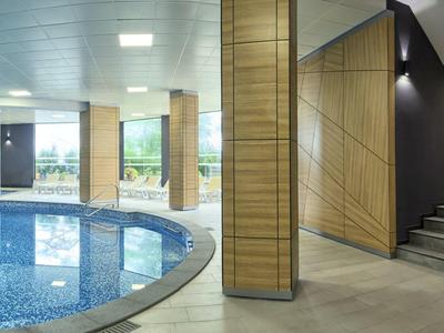 Piscine intérieure moderne avec carrelage en mosaïque et coin salon à côté des escaliers