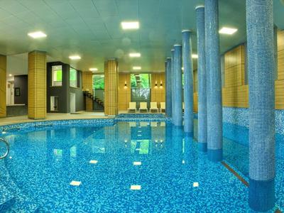 Piscine intérieure avec eau bleue, colonnes et murs jaunes dans un hôtel