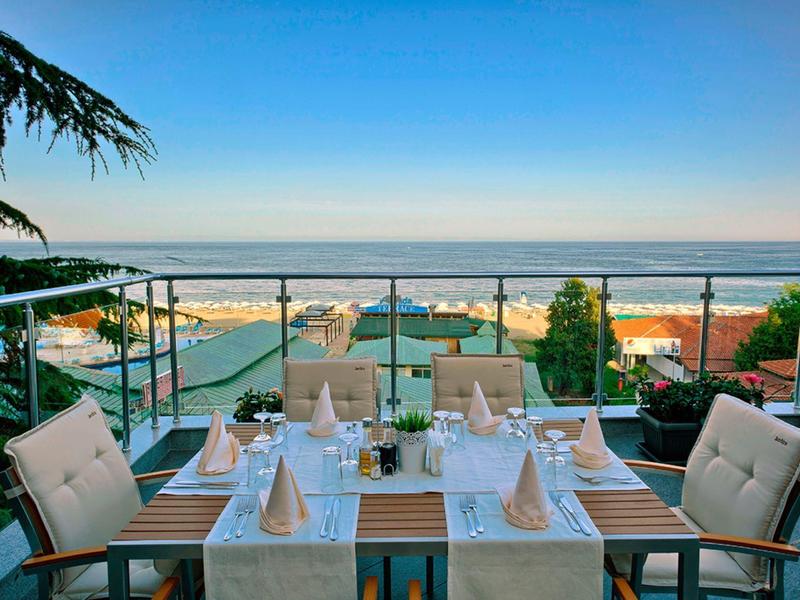 Restaurant en terrasse avec table dressée surplombant la mer sous un ciel dégagé