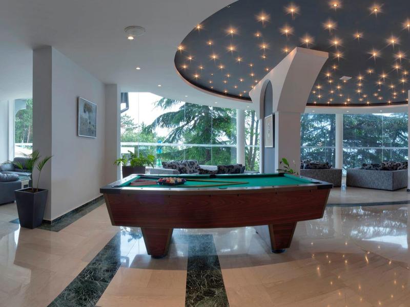 Espace de loisirs moderne avec table de billard et sièges confortables dans une pièce lumineuse.