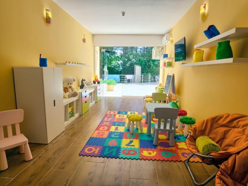 Salle de jeux avec tapis coloré, meubles pour enfants et jouets dans un espace lumineux et agréable.