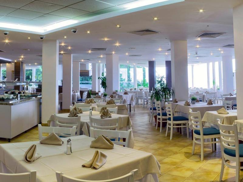 Restaurant lumineux et moderne avec des tables blanches, des chaises et des tables élégamment dressées.