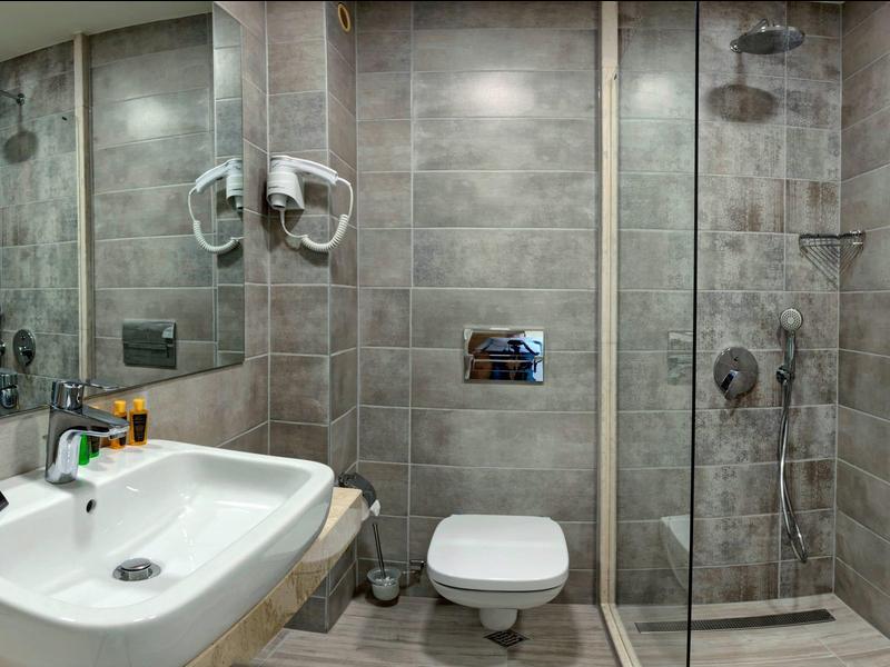 Salle de bain moderne avec lavabo, toilettes et douche à l'italienne en verre avec carrelage gris.