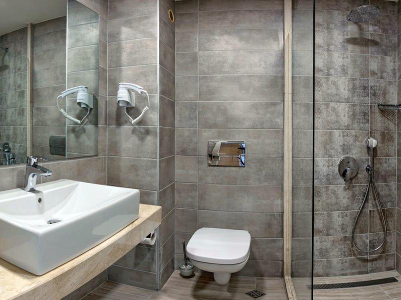 Salle de bain moderne avec lavabo, toilettes et douche carrelée gris.