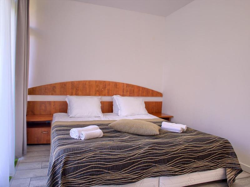 Chambre simplement aménagée avec lit double, tables de chevet et serviettes fraîches.