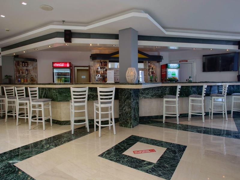 Bar d'hôtel moderne avec chaises blanches et sol en marbre.