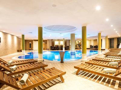 Area benessere moderna con piscina circolare, lettini e illuminazione calda.