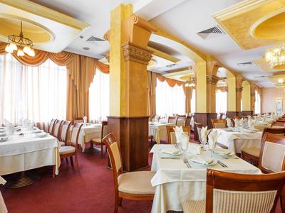 Ristorante elegante con tovaglie bianche, sedie e grandi finestre con tende.