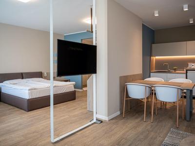Camera d'hotel moderna con letto matrimoniale, TV a parete e zona pranzo con quattro sedie.