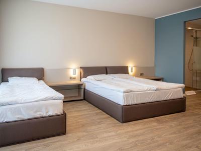 Camera d'hotel moderna con letto matrimoniale, letto singolo e design minimalista.