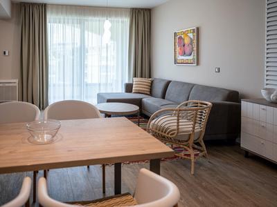 Soggiorno moderno con divano, sedia in rattan e tavolo in legno chiaro.