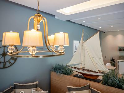 Lounge moderna dell'hotel con lampada sospesa, orologio da parete e grande decorazione a vela.