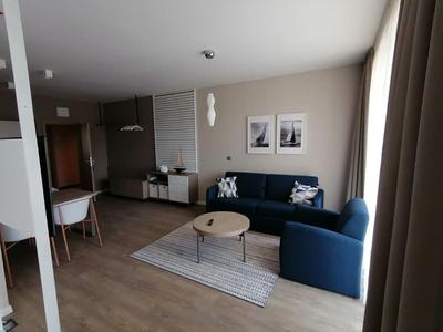 Camera d'hotel moderna con divano blu, tavolo da pranzo e decorazioni minimaliste.