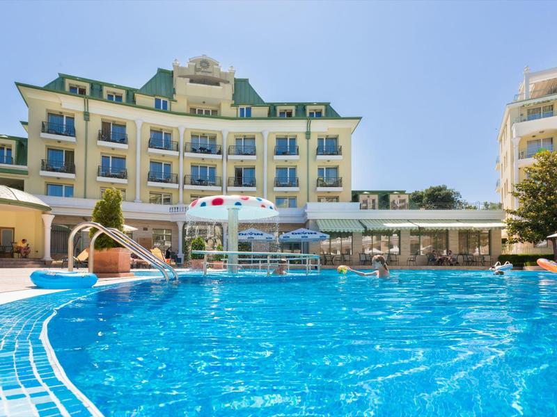 Grande piscina blu davanti a un edificio di hotel su più piani in una giornata di sole.