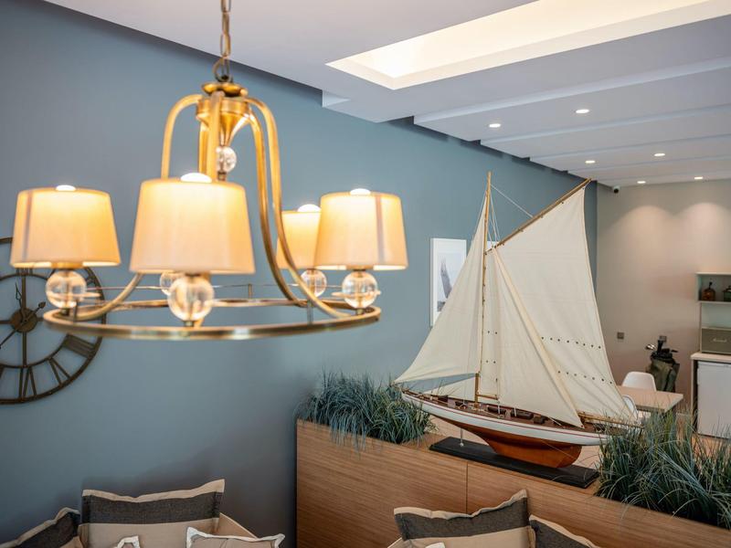 Lounge moderna dell'hotel con lampada sospesa, orologio da parete e grande decorazione a vela.