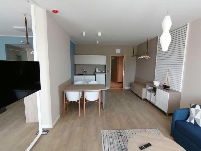 Area moderna della camera d'albergo con TV, tavolo da pranzo, lavabo e zona salotto.