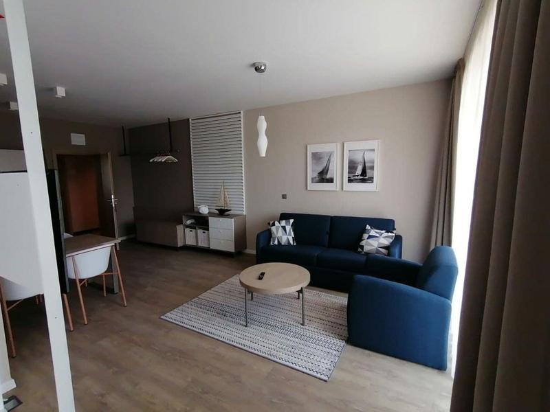 Camera d'hotel moderna con divano blu, tavolo da pranzo e decorazioni minimaliste.