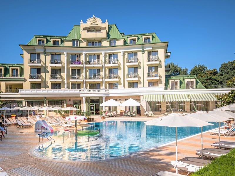 Hotel con grande piscina e più ombrelloni sotto un cielo azzurro