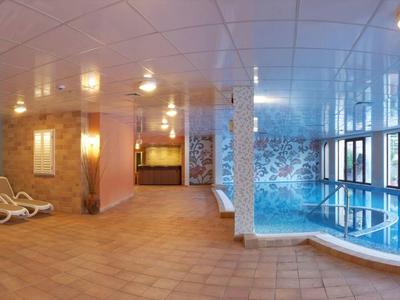 Licht overdekt zwembad met ligstoelen en grote ramen