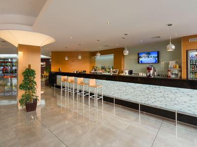 Moderne hotelbar met lange toonbank, hoge krukken en warme verlichting.
