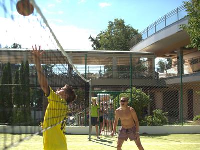Twee jonge mannen spelen volleybal op een binnenplaats met moderne architectuur op de achtergrond.