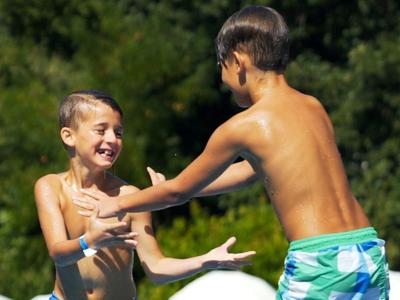Twee jongens spelen buiten met water op een zonnige dag.