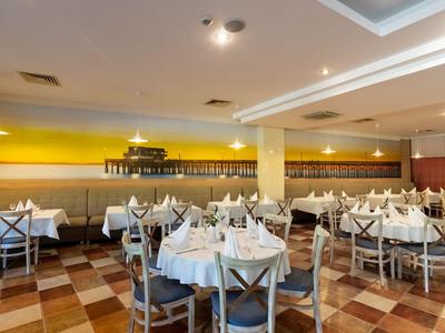 Licht hotelrestaurant eetzaal met gedekte tafels en stoelen.