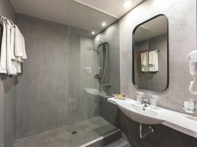 Modernes Bad mit freistehender Dusche, Waschbecken, großem Spiegel und Handtüchern an der Wand.
