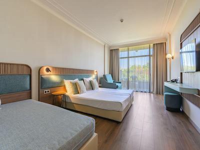 Modern ingerichte hotelkamer met twee bedden, zithoek en groot raam met uitzicht naar buiten.