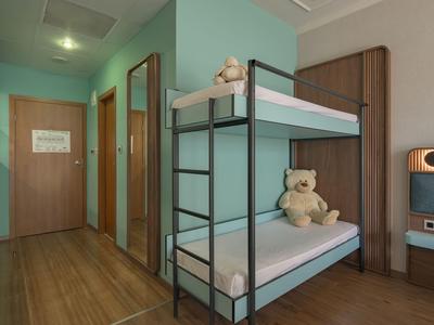 Kinderzimmer mit Etagenbett, Teddy und Holzboden in einem Hotel.