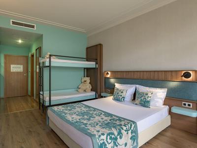 Modern eingerichtetes Hotelzimmer mit Doppelbett, Etagenbett und hellem Holzboden.